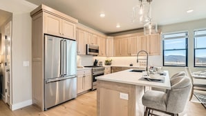 A modern kitchen with stainless steel appliances, wooden cabinets, and a large island with bar stools.