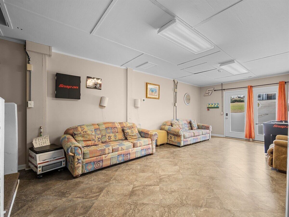 A spacious living room with two patterned sofas, a small table, and a refrigerator.