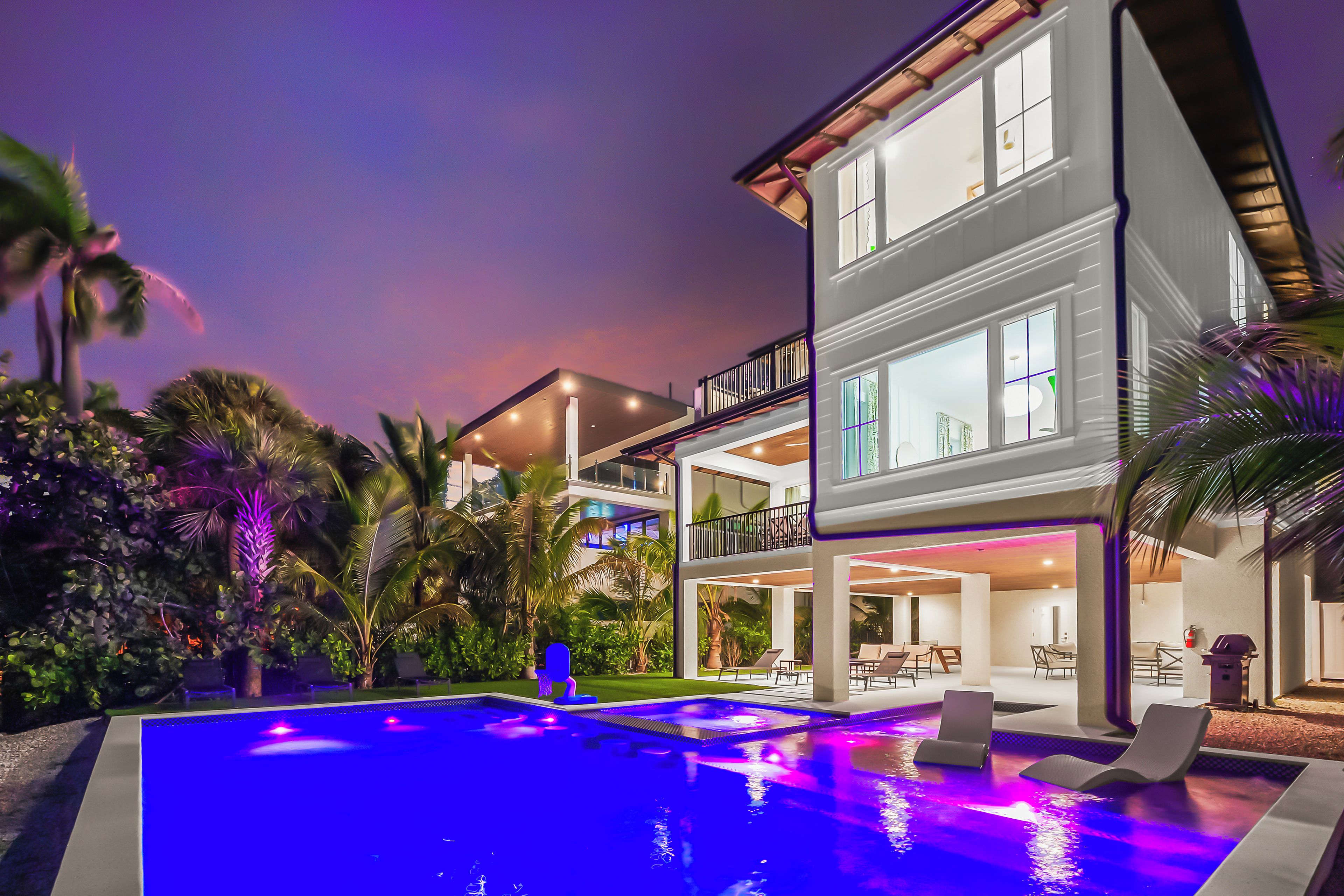 A modern two-story house with a swimming pool and outdoor seating.