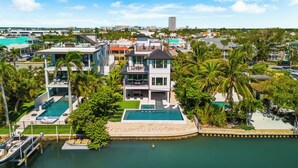 A modern multi-story hotel with multiple swimming pools, a marina, and lush greenery.
