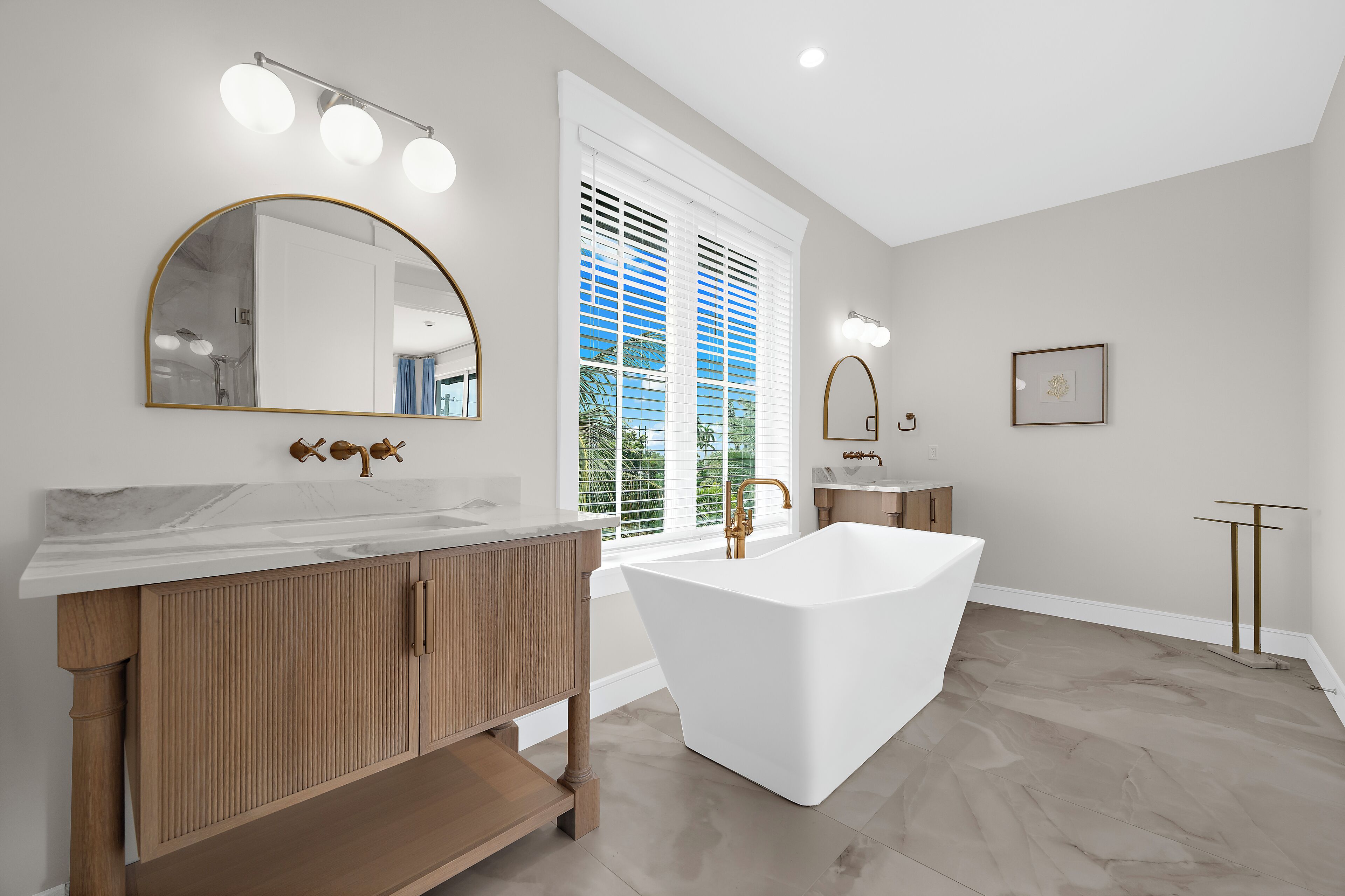 Un bagno moderno con una vasca freestanding, un mobile lavabo con piano in marmo e uno specchio grande.