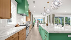 A modern kitchen with a large island, wooden cabinets, and a view to the outside.