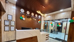 Un'area reception con una scrivania in legno, certificati incorniciati appesi al muro e orologi che mostrano l'ora di diverse città.