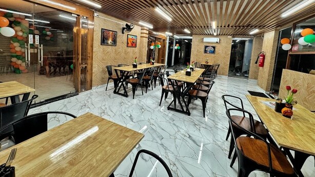 Un ristorante con tavoli e sedie in legno, pavimento in marmo e soffitto in legno.