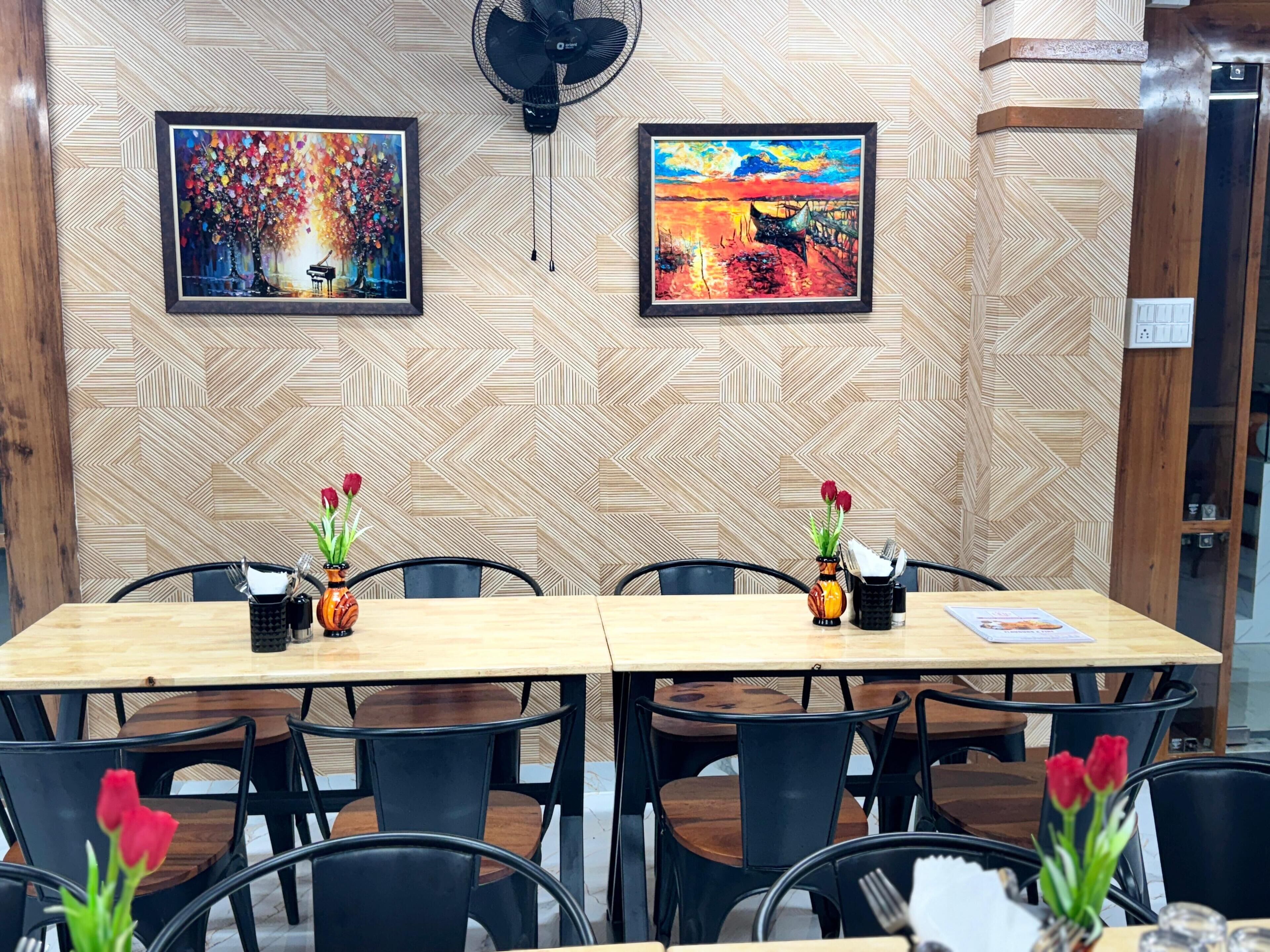A conference room with two tables, chairs, and two framed paintings on the wall.