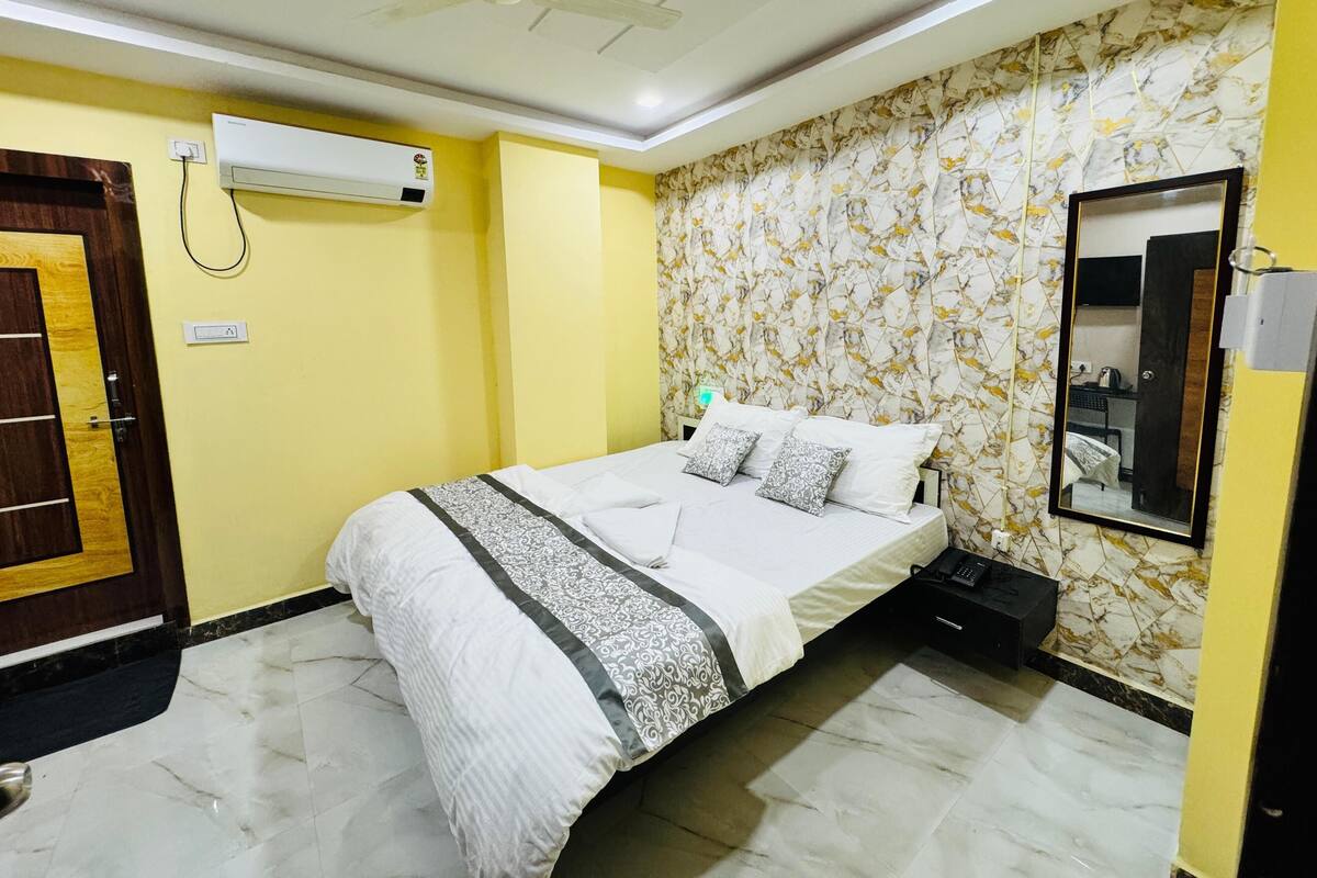 Une chambre d’hôtel équipée d’un lit, d’un ventilateur de plafond, d’un appareil de climatisation, d’un miroir et d’une porte.