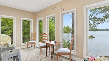 Un espace repas comprenant une table, des chaises et donnant sur un lac.
