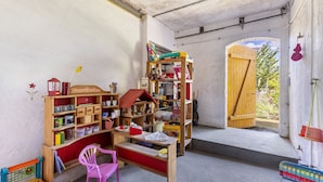A room with a wooden desk, a pink chair, and a bookshelf filled with various items.