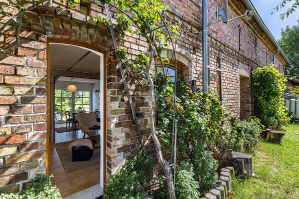 A brick building with a doorway leading to an interior space with a sofa and a table.