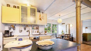 A kitchen with yellow cabinets, a stove, and a dining area with a table and chairs.