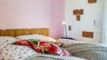 Een bed met bloemenbeddengoed, een houten hoofdbord en een muur met een lichtschakelaar en stopcontact.
