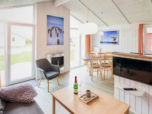 Uma sala de estar moderna com lareira, área de jantar e cozinha.
