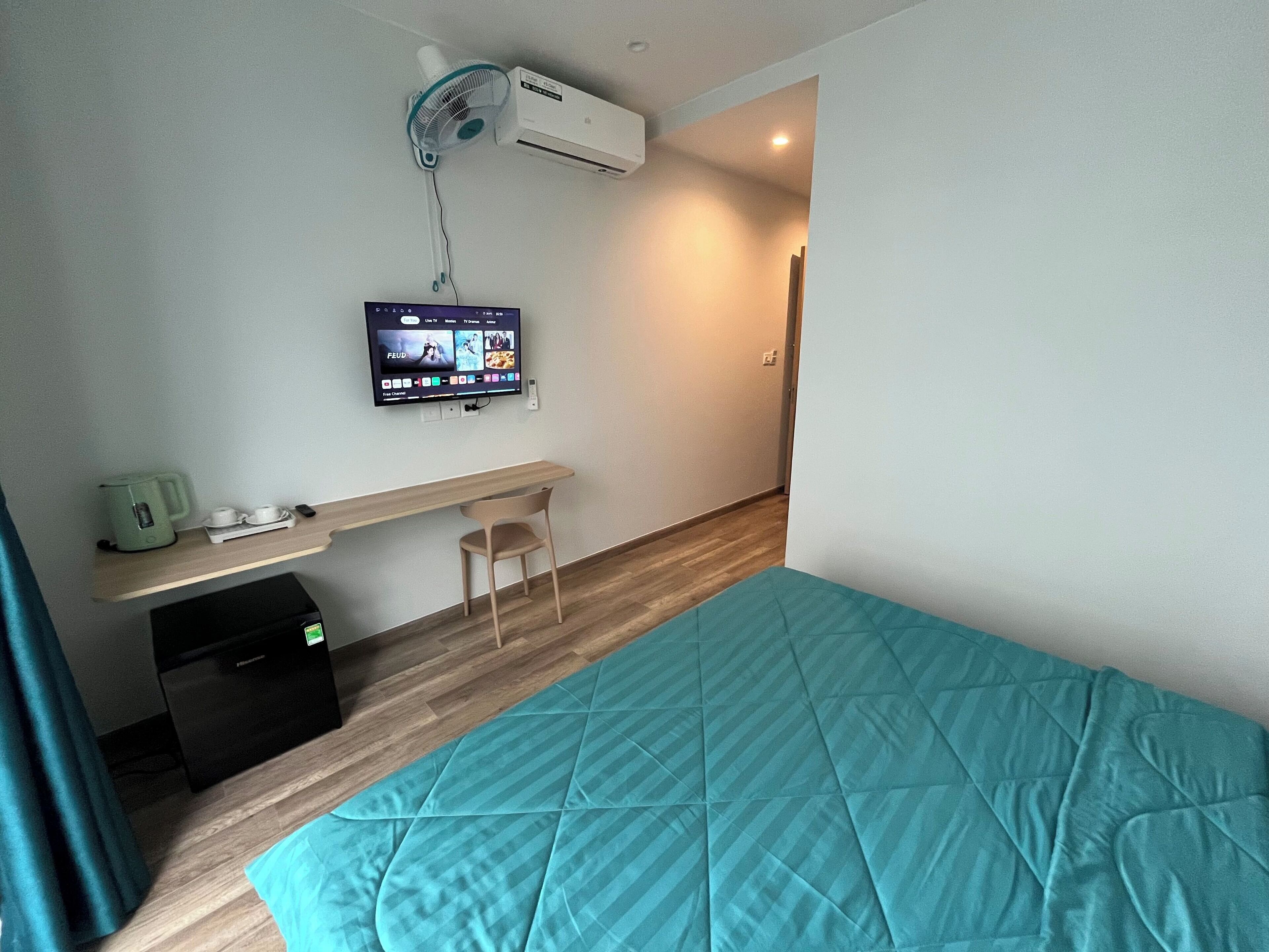 Une chambre d’hôtel équipée d’un lit, d’un bureau, d’une chaise, d’une télévision et d’un appareil de climatisation.