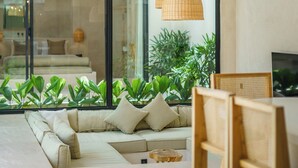 Un salon moderne avec un canapé, une table à manger en bois et des lampes suspendues en osier.