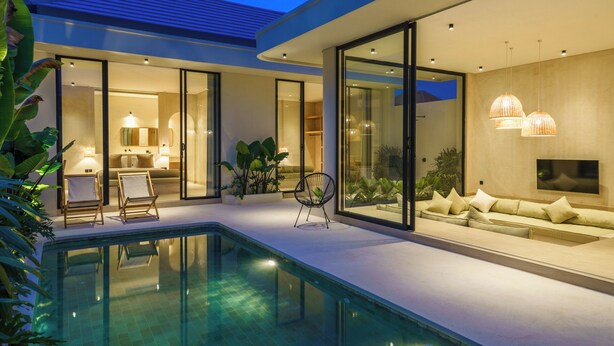 Une maison moderne dotée d’une piscine, de portes vitrées donnant sur un espace de vie avec un canapé et un téléviseur, ainsi que d’un coin repas avec des chaises et une table.