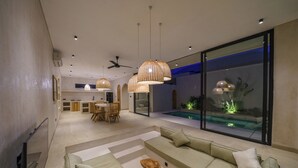 Un salon moderne doté d’un grand canapé, d’un coin repas et offrant une vue sur une piscine.