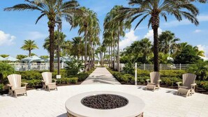 A pathway lined with palm trees and outdoor seating areas.