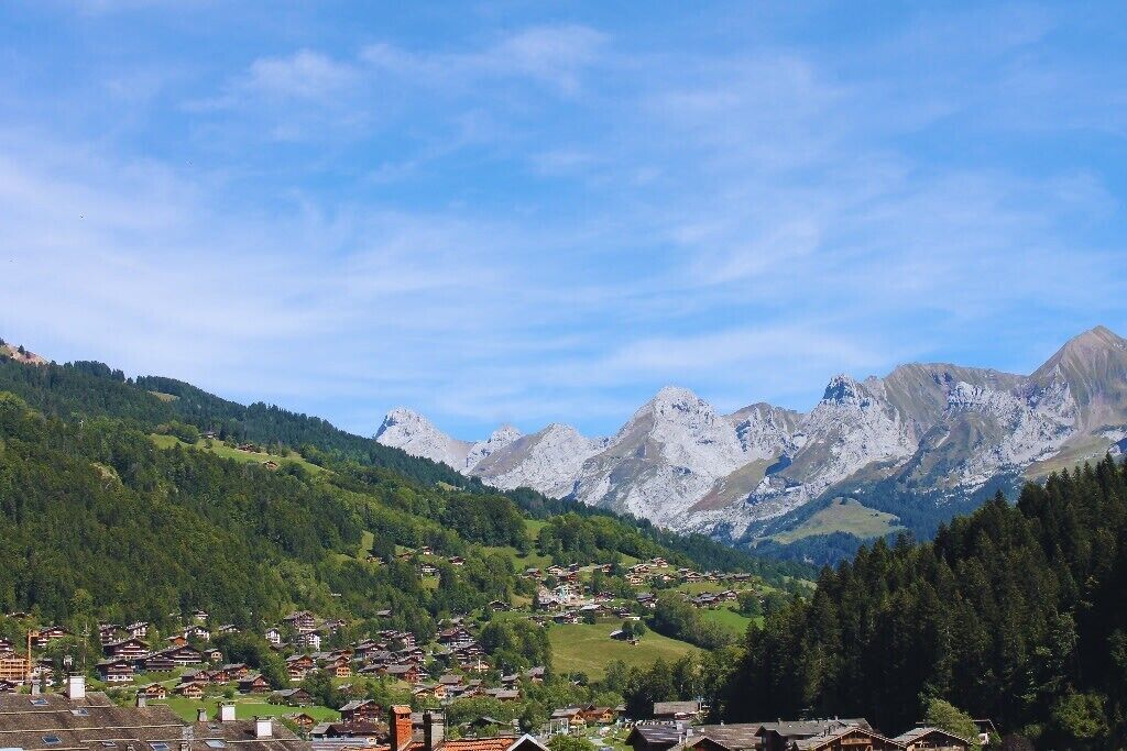 A mountain village with traditional houses, a clear sky, and a backdrop of rugged mountains.