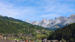 Un village de montagne aux maisons traditionnelles, sous un ciel dégagé, avec en toile de fond des montagnes escarpées.