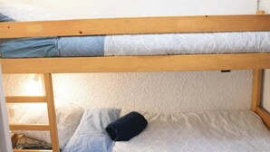 Un lit superposé avec une structure en bois et une literie à motifs.