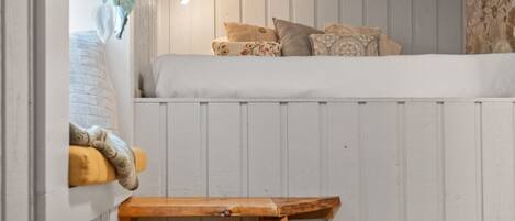 A cozy room with a bunk bed, a wooden bench, and a patterned rug.