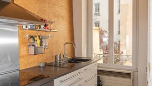 Eine Küche mit einer Edelstahl-Dunstabzugshaube, einem Spülbecken und einem Fenster mit Blick auf ein Gebäude.