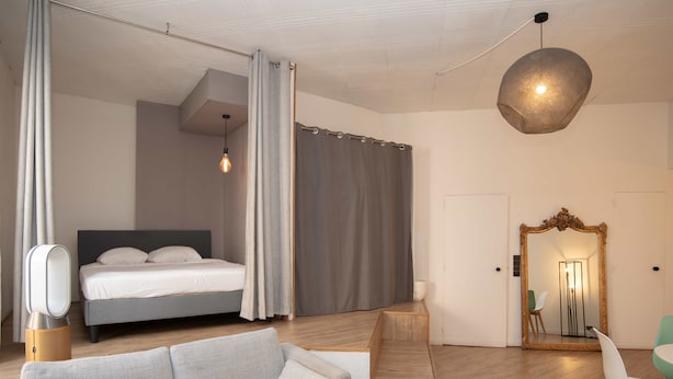 Ein modernes Hotelzimmer mit einem Bett, einer Couch, einem Spiegel und Holzboden.