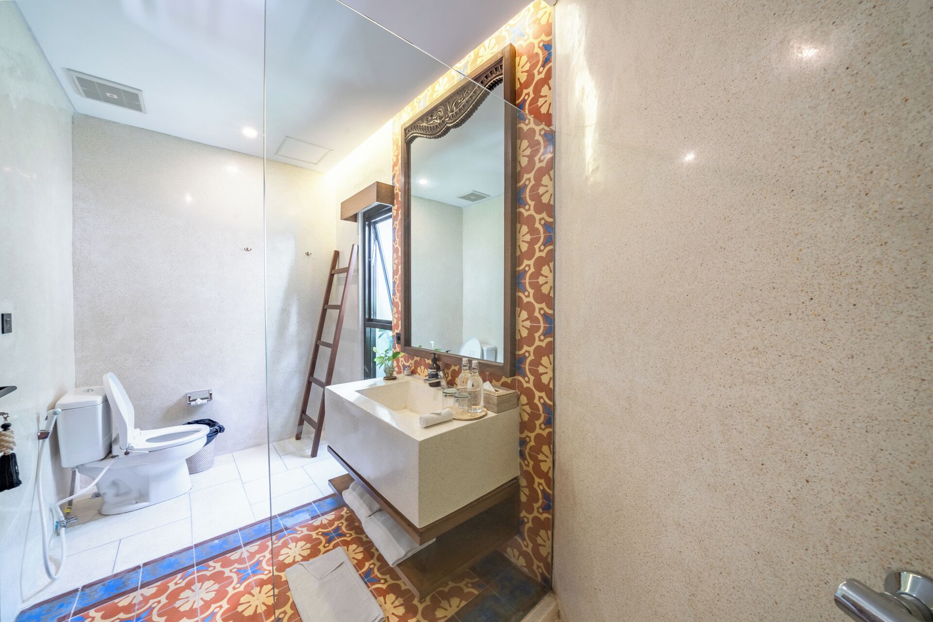 Un baño con inodoro y lavamanos blancos, y un espejo grande.