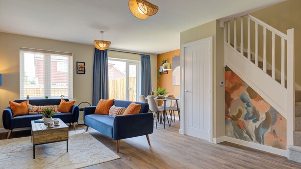 A living room with a blue sofa set, a wooden coffee table, and a dining area with a white table and chairs.