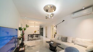 Ein modernes Wohnzimmer mit Flachbildfernseher, einer Couch, einem Couchtisch und einem Essbereich mit Stühlen und einem Tisch.