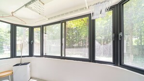 Ein Zimmer mit großen Fenstern, einer Waschgelegenheit und Blick auf Bäume.