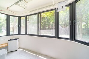 A room with large windows, a laundry area, and a view of trees. - Book and Bed - SML Center (Shanghai)