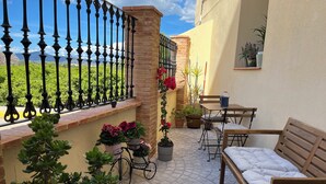 Une terrasse avec un banc en bois, une table et des plantes en pot.