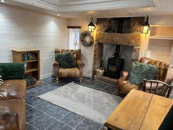 Una sala de estar acogedora con muebles de cuero, una chimenea y una pared de piedra.