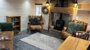 A cozy living room with a stone fireplace, leather furniture, and a bookshelf. - Cozy Seaside Retreat in Peterhead (Peterhead)