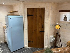 Una habitación con un refrigerador azul claro, una puerta de madera, un reloj en la pared y un sofá de cuero marrón.