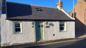 A small, single-story building with a green door, two windows, and a chimney. - Cozy Seaside Retreat in Peterhead (Peterhead)