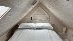 A small, cozy room with a sloped ceiling, a bed with white bedding, and a wooden headboard. - Cozy Seaside Retreat in Peterhead (Peterhead)