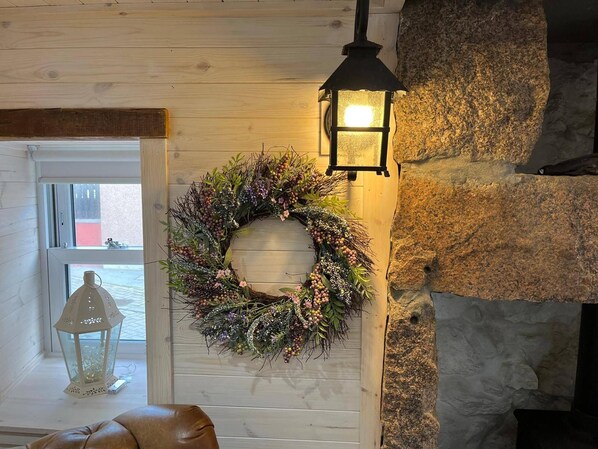 A room with a wooden wall, a stone wall, a hanging lantern, and a wreath. - Cozy Seaside Retreat in Peterhead (Peterhead)