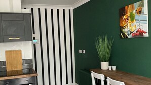 Eine moderne Küche mit Holzarbeitsplatte, Wand in Schwarz-Weiß-Streifen und einem Essbereich mit weißen Stühlen.