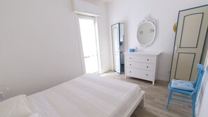 A bedroom with a bed, a dresser, a mirror, and a chair. - Villetta Blu sul Mare a Fontane Bianche by Wonderful Italy (Syracuse)