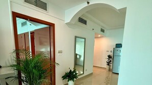 Un hall d’entrée spacieux au design moderne, agrémenté d’une grande plante en pot, d’un miroir et d’un réfrigérateur.
