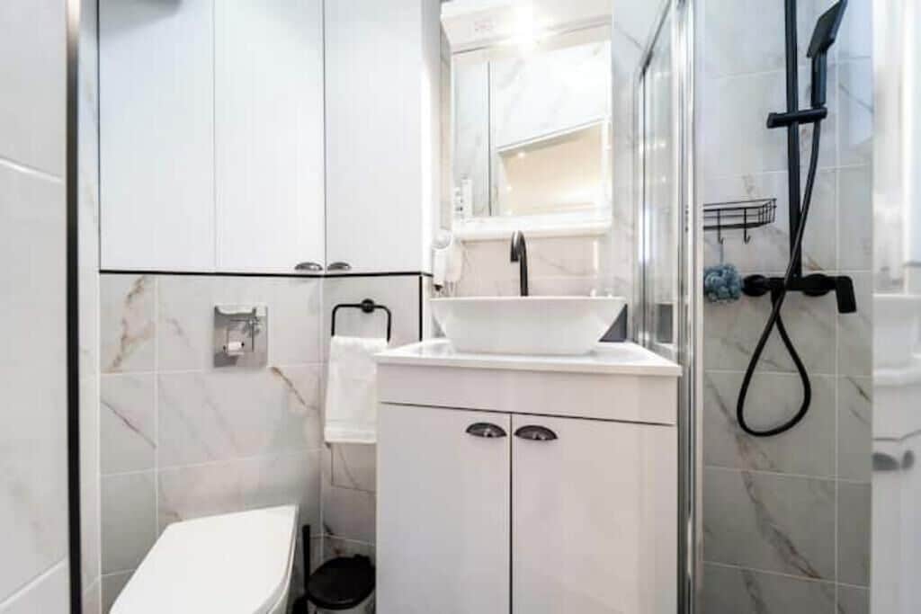Un baño moderno con un lavabo blanco, un espejo y cabina de ducha.