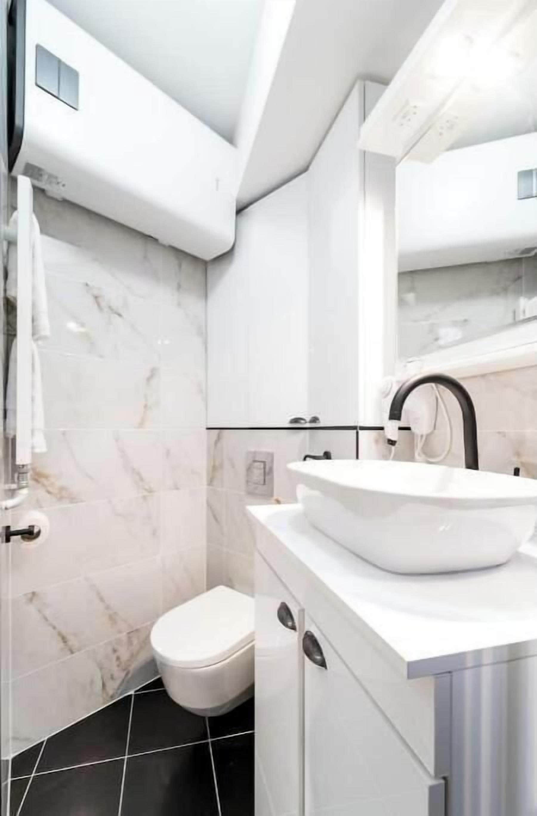 Un baño moderno con un lavabo blanco, un inodoro y una zona de ducha.