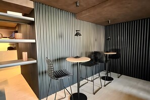 Um interior moderno com parede em listras verticais, uma mesa redonda, duas cadeiras e um lustre suspenso.