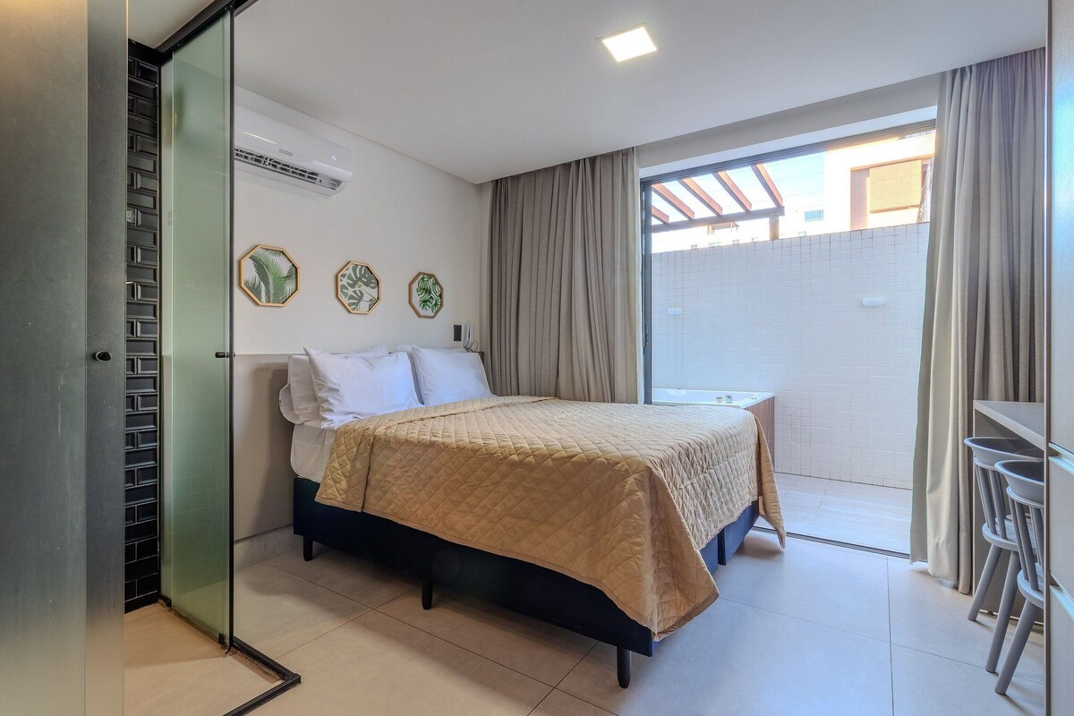 A bedroom with a bed, a small table, a chair, a sliding door, and a view of the outside.