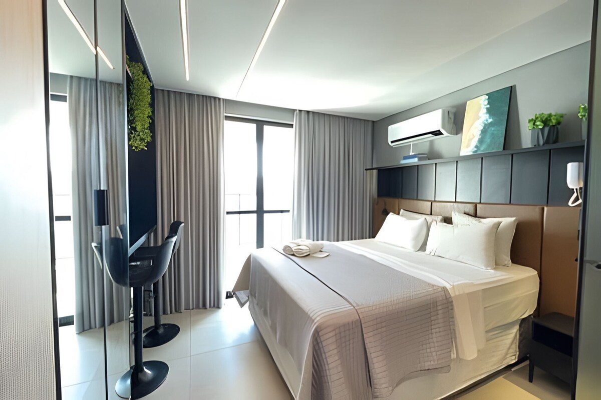 A modern hotel room with a large bed, a desk, and a chair.