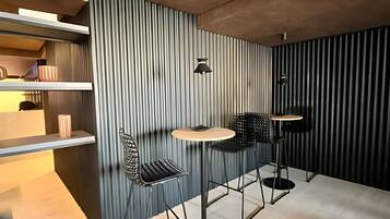 Um interior moderno com parede em listras verticais, uma mesa redonda, duas cadeiras e um lustre suspenso.