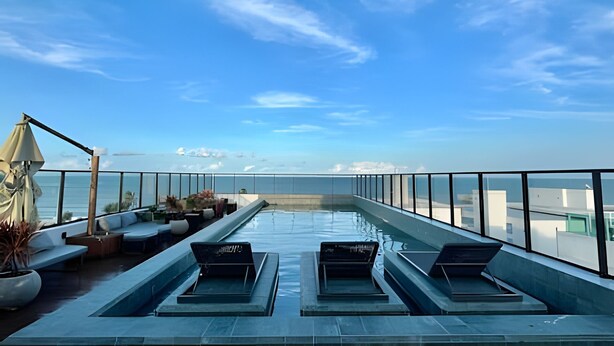 A rooftop pool with lounge chairs and a view of the ocean. - Get By Side (João Pessoa)