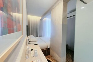 A hotel room with a bed, a bedside table with a bottle and a glass, and a window with curtains. - Hako Hotel Tun Aminah (Sekudai)